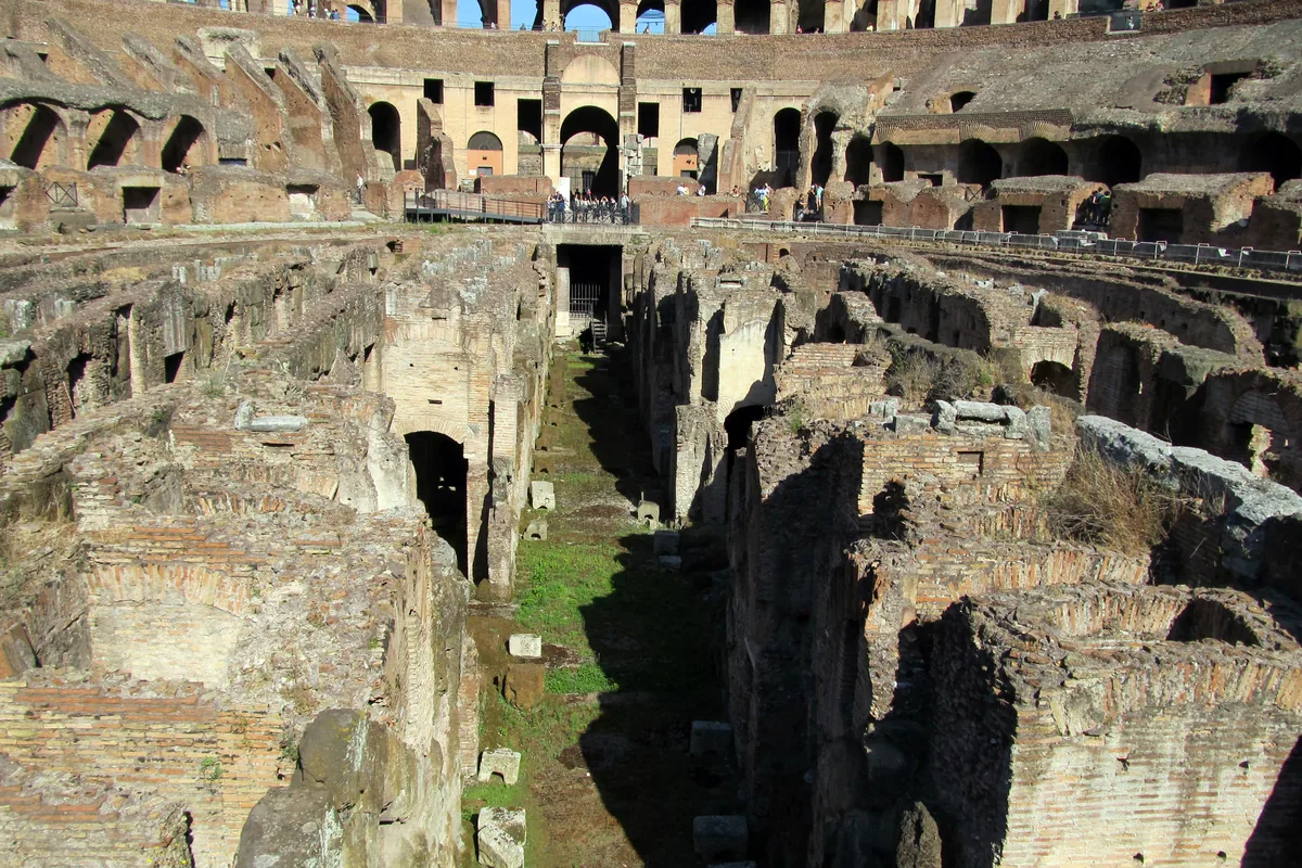 The exposed underground passages of the Colosseum, with long brick walls and arched openings below the arena level